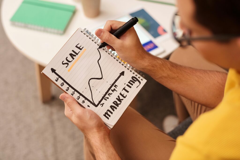 person drawing a graph on a notepad showing an incresing line to illustrate improving Campaign Performance and scale of marketing campaign.