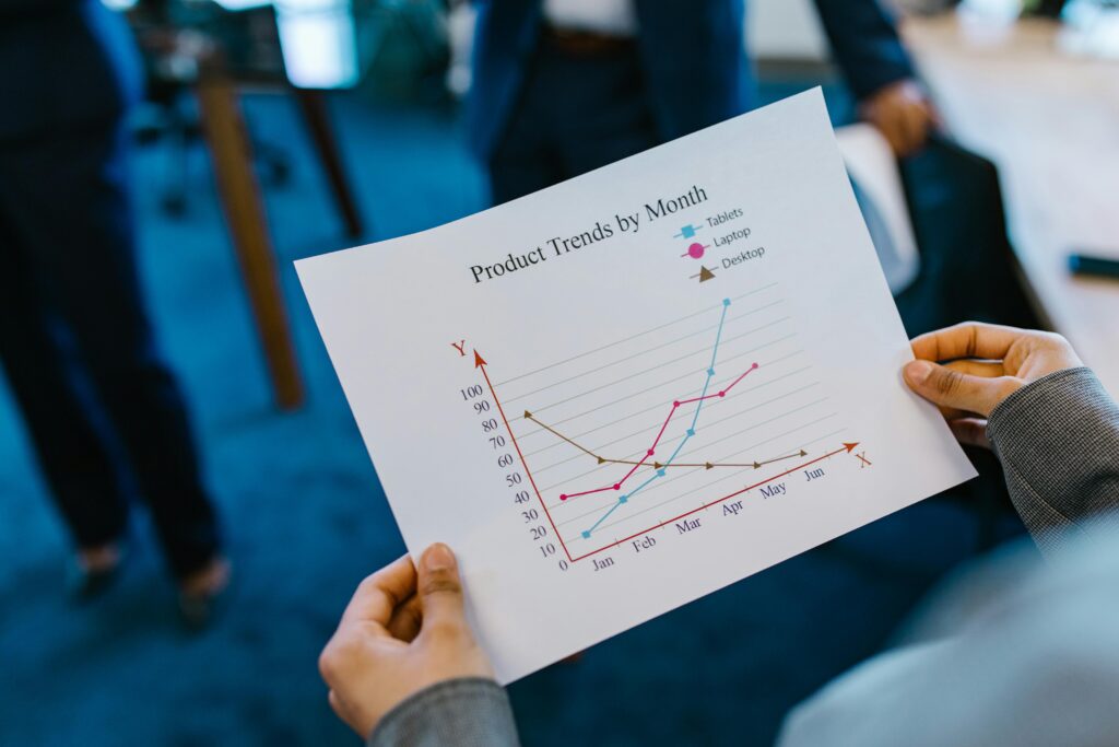 Person analyzing a printed line graph showing monthly product trends to evaluate Campaign Performance and marketing campaign growth.